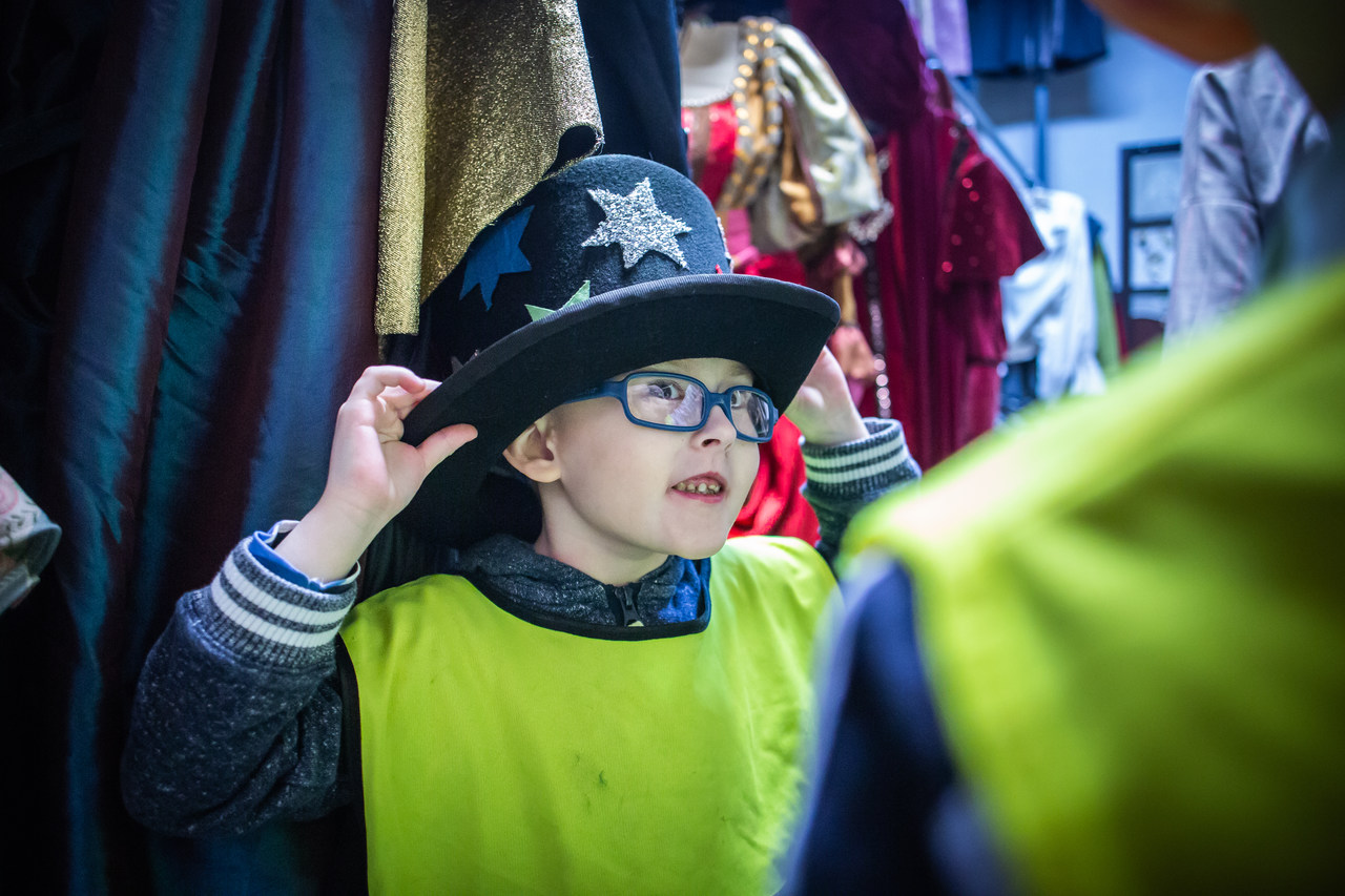 Mały chłopiec przymierza w garderobie duży kapelusz z gwiazdami